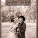 A couple posing under a Happy Trails sign in Denver, Colorado